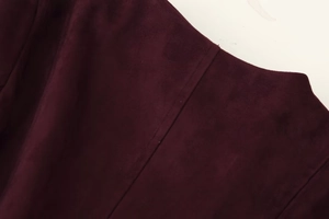 Detailed close-up of seams and collar on a dark burgundy suede jacket for women