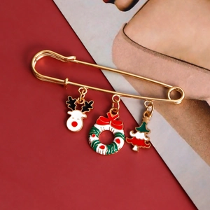 Christmas safety pin brooch with enamel reindeer, wreath, and tree charms on red background