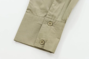 Detail of the khaki green shirt showing the buttoned cuff and high-quality poplin texture