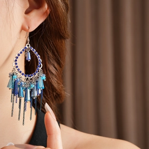 Dettaglio di orecchini vintage con nappe di zirconi blu indossati da una modella elegante