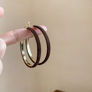 Detail showing the brown flocked texture and gold metallic inner of circular earrings