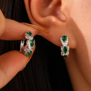 Macro view of teardrop green zircon drop earrings with pave white stones on earlobe