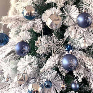 Close-up of blue and silver ornaments with glitter on a snowy Christmas tree