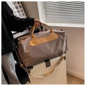 Brown nylon travel bag with PU handles placed on white luggage in travel setting