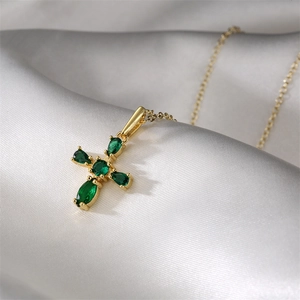 Collier croix dorée avec cristaux verts en forme de goutte sur soie blanche