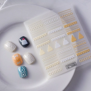 Close-up of 5D embossed nail stickers featuring white knitting patterns and winter motifs