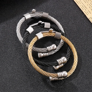 Macro view of three-color stainless steel wire rope bracelets with ball ends on dark background