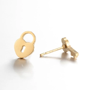 Asymmetric gold lock and key earrings with a polished finish on a white background