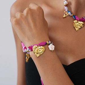 Detail of pink floral ribbon necklace with golden heart and smiley face pendants