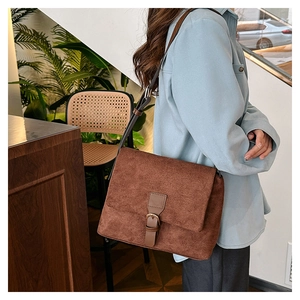 Lifestyle view of a vintage dark brown matte crossbody bag worn over a light blue shirt