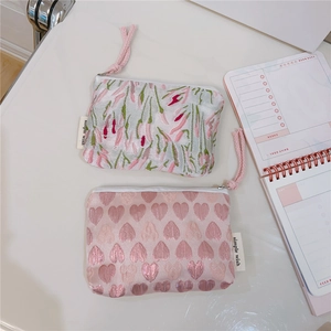 Detail of floral and heart embroidery on pink and green jacquard fabric mini pouches