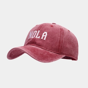 Side view of vintage washed red cotton baseball cap with white NOLA letter embroidery