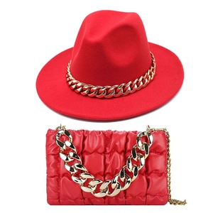 Detail of red fedora hat and quilted leather bag with chunky gold chain accents