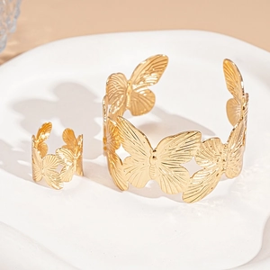 Detailed view of golden butterfly jewelry set with open ring and cuff on white ceramic tray