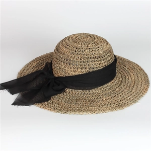 Detail of elegant bowknot and textured woven straw on a foldable wide brim sun hat
