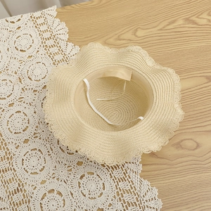 Détail intérieur du chapeau de paille beige avec cordon coupe-vent et bord ondulé