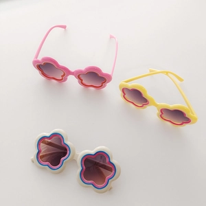 Flat lay macro of flower-shaped kids sunglasses in pink, yellow, and cream tones