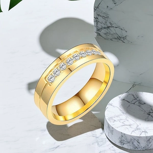 Détail d'une large bague pour homme en acier doré avec incrustation de diamants sur marbre