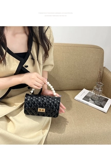 Detail of black quilted mini jelly bag with pearl handle and golden square twist lock