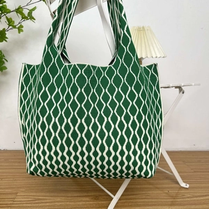 Detailed view of large green knit tote bag with wavy geometric pattern and dense texture