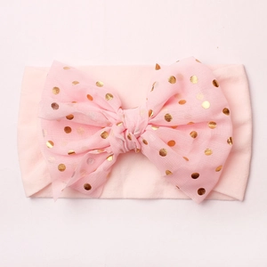 Pink nylon baby headband with gold polka dot bow accent on a clean white background