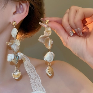 Detailed shot of irregular shell tassel earrings with gold finish and resin accents