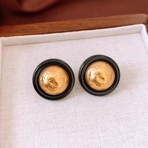 Macro view of vintage gold textured dome earrings with elegant black circular rims