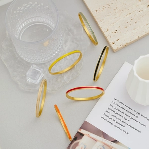 Detail of colorful enamel gold-plated stainless steel bangles in a luxury lifestyle setting