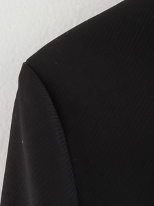Close-up of shoulder seam and twill texture on a black long-sleeve blazer jacket