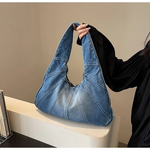 Détail du sac sous le bras en denim bleu avec coutures apparentes et fermeture éclair