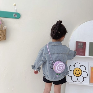 Girl wearing a purple lollipop-shaped crossbody bag with a white spiral pattern