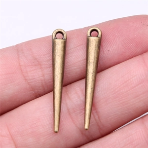 Close-up of vintage bronze cone pendant held in hand showing small size and metal texture