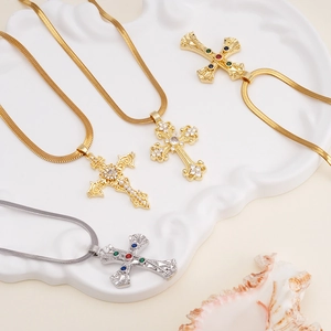 Golden and silver cross necklaces with colorful zircon stones on a white relief tray