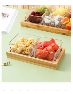 Detail view of square glass fruit bowls with gold rims on a natural wooden tray