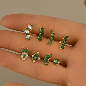 Detailed close-up of eight gold S925 silver ear studs featuring sparkling green and white stones