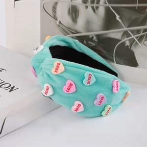 Detail of mint green plush headband with colorful heart charms and XOXO lettering
