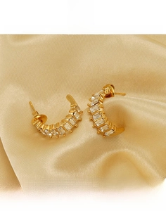 Close-up of gold titanium steel U-shaped earrings with rectangular zircon inlay details