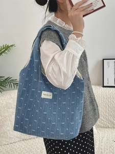 Sac cabas en jean bleu avec motif nœud blanc et imprimé cœur porté par mannequin