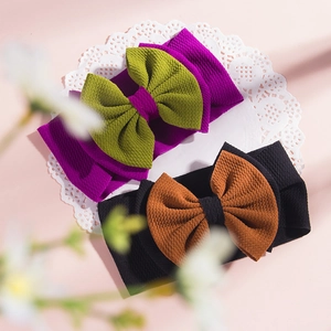 Detail of waffle texture baby headbands with large bows in purple and black