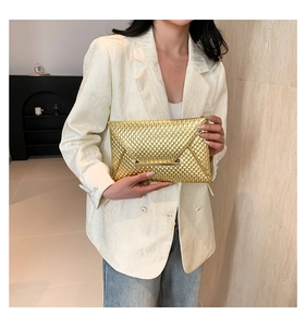 Detail of a gold envelope clutch with fish scale texture and a metallic bar closure