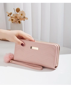 Detail of pink wave-patterned wallet featuring double zippers and a soft fur pompom charm