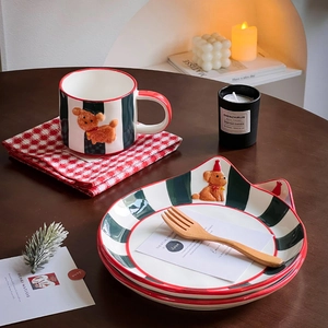 Detail of a ceramic mug set with green stripes and a 3D puppy on a wooden table