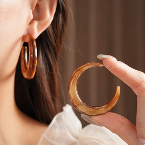 Detailed view of amber resin C-shaped hoop earrings with unique marble texture patterns