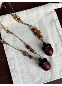 Detail of wooden hazelnut pendants with beads on a natural linen bag and dark wood surface