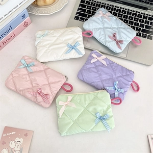 Five pastel quilted cosmetic pouches with decorative bows in a fan-shaped lifestyle arrangement