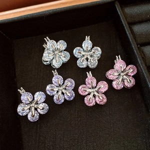 Vue macro de boucles d'oreilles fleurs en zircon blanc, violet et rose sur plateau noir