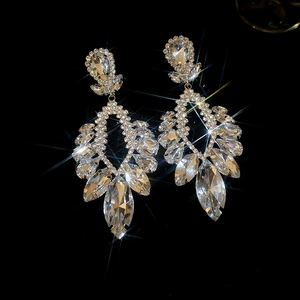 Détail macro de boucles d'oreilles pendantes argentées avec strass sur fond noir