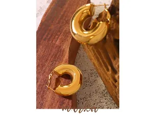Polished gold U-shaped chunky hoop earrings placed on a rustic wooden decorative stand