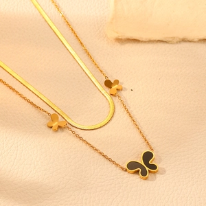 Detailed close-up of double-layered gold butterfly necklace with sleek flat snake chain