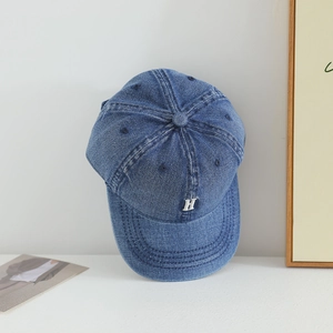 Close-up of a blue denim kids' baseball cap with a silver H letter embroidery
